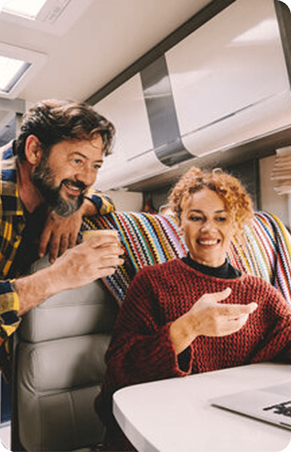 Two people sitting at a table with a laptop, discussing RV sale