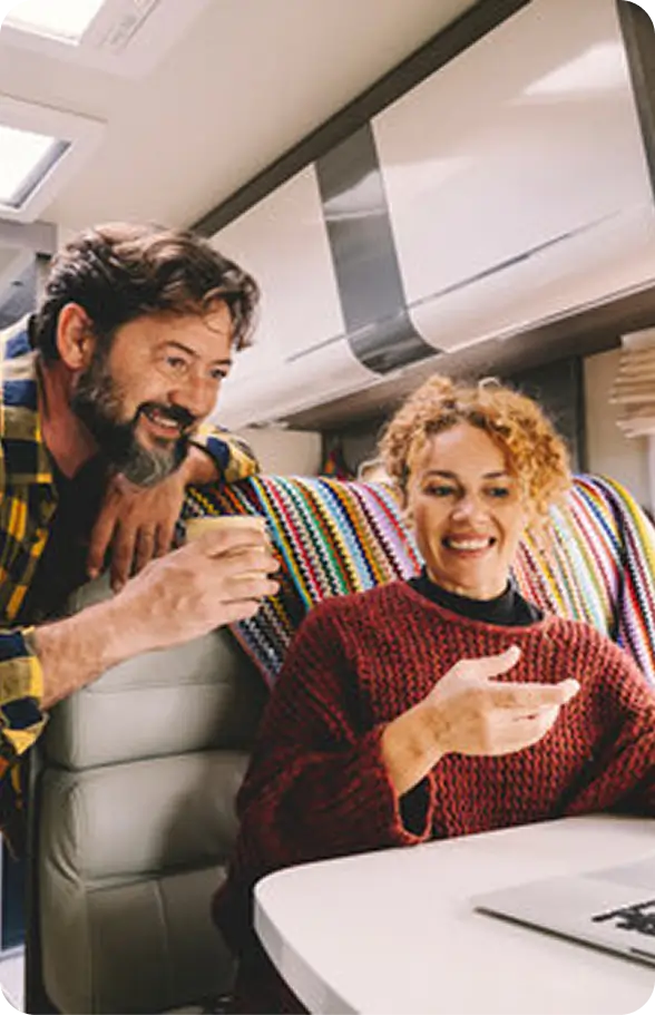 Two people sitting at a table with a laptop, discussing RV sale